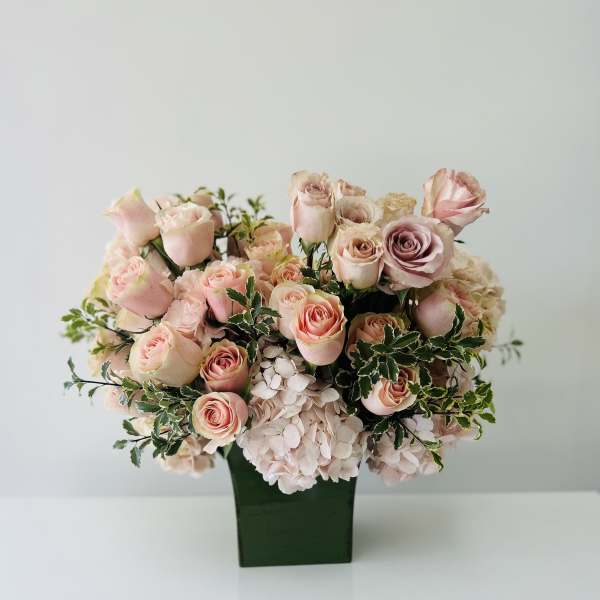 Pink roses and pale hydrangeas arranged in a green vase