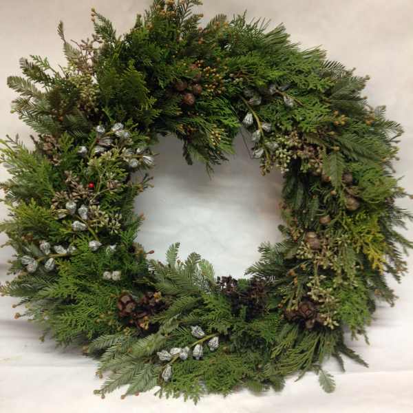 A large evergreen wreath with pinecones and silver accents