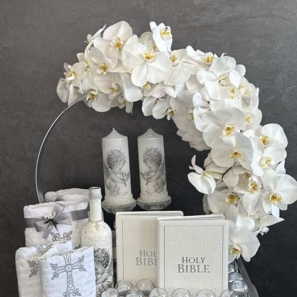 White orchid arrangement with candles, Holy Bibles, and religious keepsakes