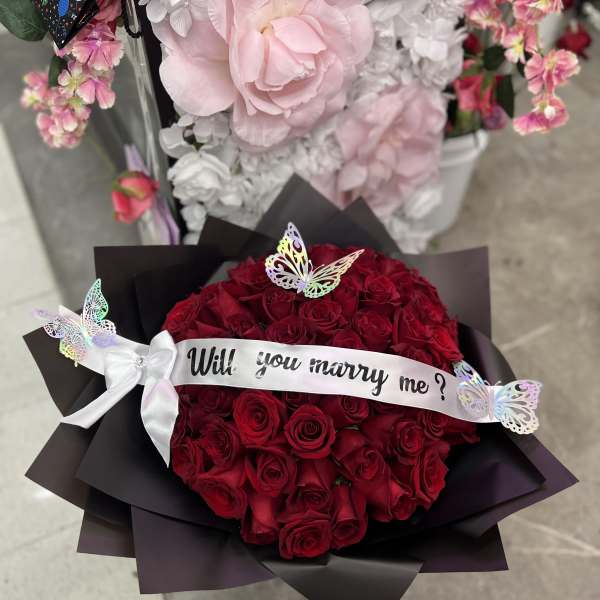 Bouquet of red roses with a "Will you marry me?" ribbon and butterflies