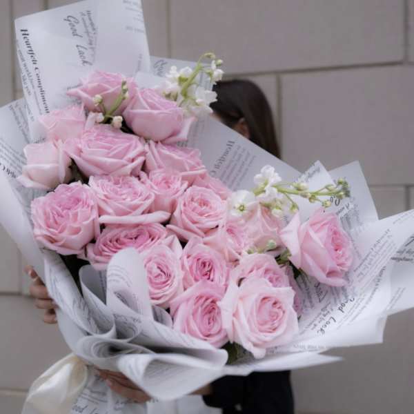 Large bouquet of pale pink roses wrapped in white paper