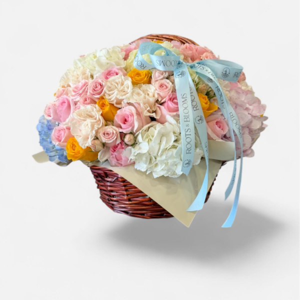 Basket of pastel roses and hydrangeas with a blue ribbon