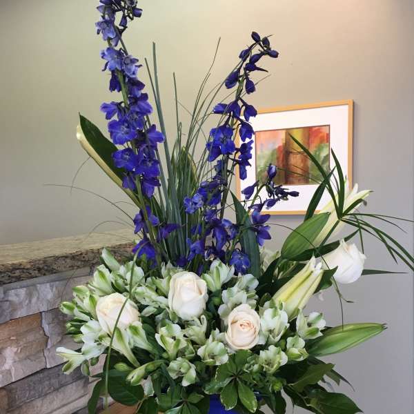 Tall blue and white floral arrangement in a blue vase