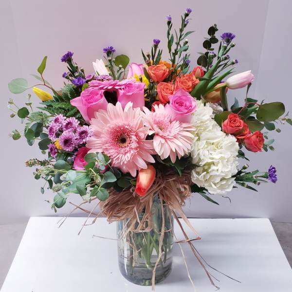 Mixed bouquet of pink and coral flowers in a glass vase
