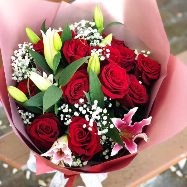 Bouquet of red roses and pink lilies wrapped in pink paper