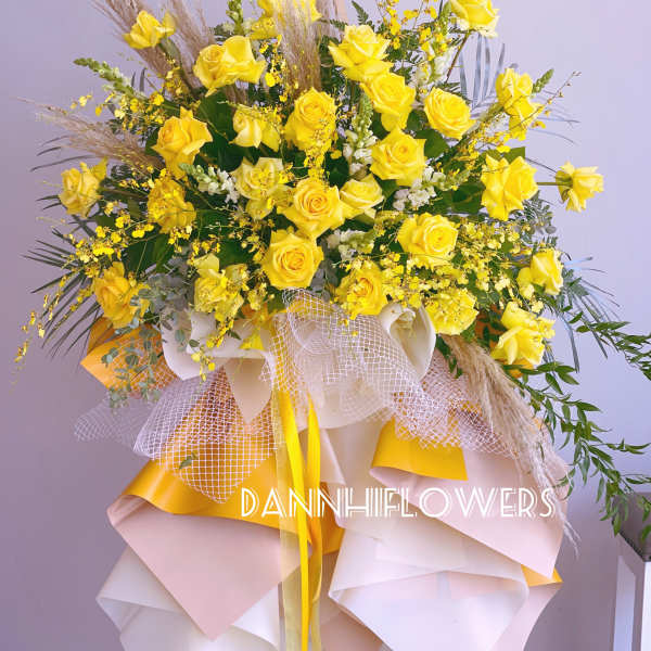 Large bouquet of yellow roses with decorative grasses and ribbon wrap