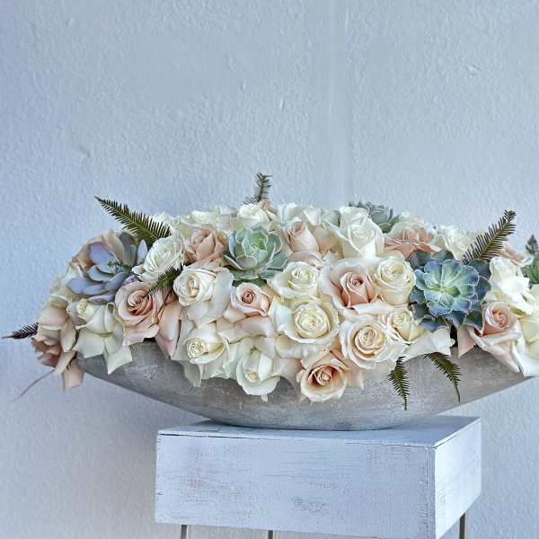 Low arrangement of pale roses and succulents in a shallow bowl