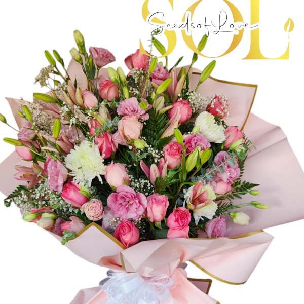 Pink bouquet with roses, lilies, and white filler flowers wrapped in blush paper