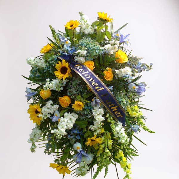 Large sympathy spray with yellow sunflowers, blue flowers, and a ribbon