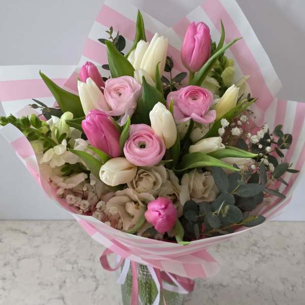 Pink and white mixed bouquet with tulips and ranunculus in striped wrap
