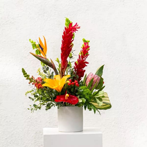Tropical flower arrangement in a white cylindrical vase