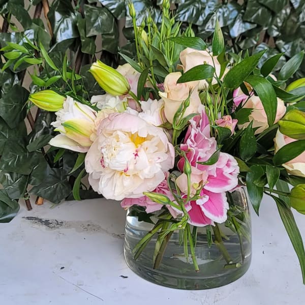 Pink and white flowers arranged in a clear glass vase