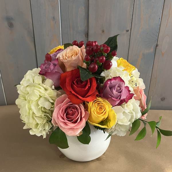 Colorful rose and hydrangea arrangement in a white vase
