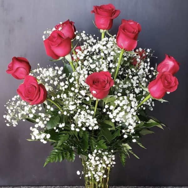 Pink roses arranged in a clear glass vase with white baby's breath