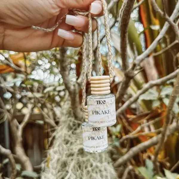 Hand holding two small hanging candle bottles in a tree