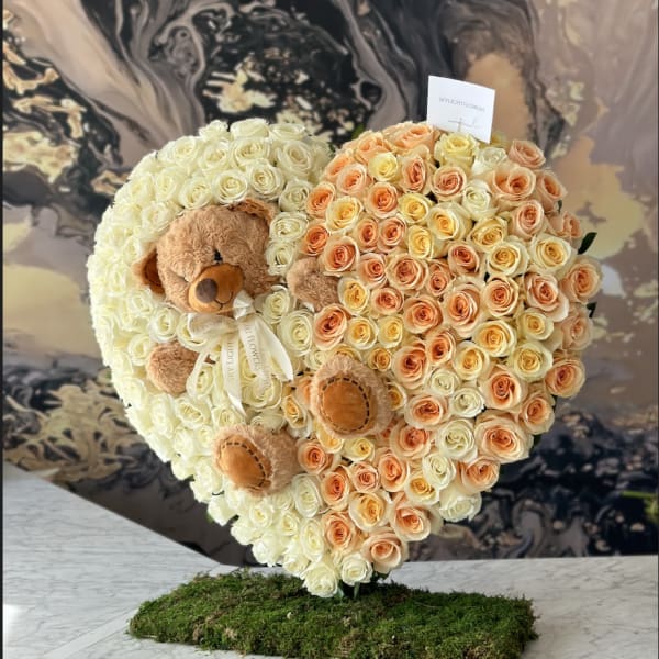 Heart-shaped rose arrangement with two teddy bears on a moss base
