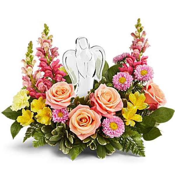 Low arrangement of peach roses and mixed pink and yellow flowers with a glass angel figurine in the center