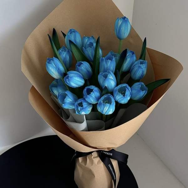 Bouquet of bright blue tulips wrapped in brown paper