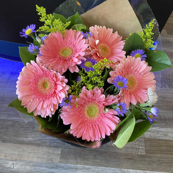 Pink gerbera daisy bouquet with purple accent flowers and greenery