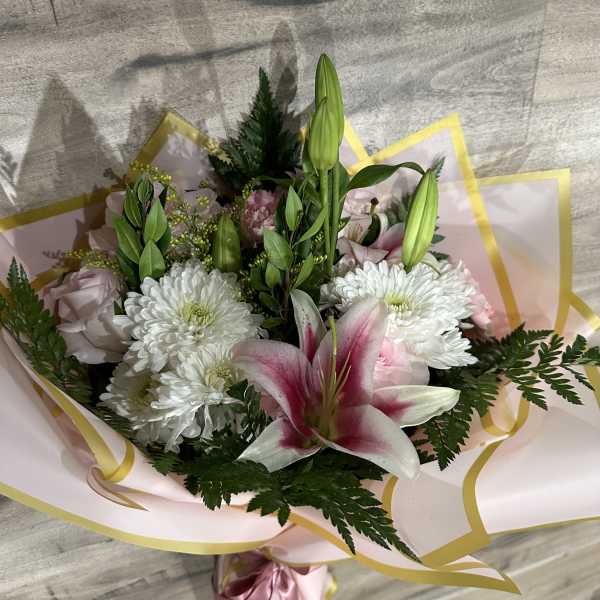 Bouquet of white chrysanthemums and pink lilies wrapped in pink paper