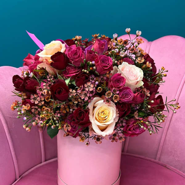 Bouquet of pink, red, and cream roses in a pink hat box