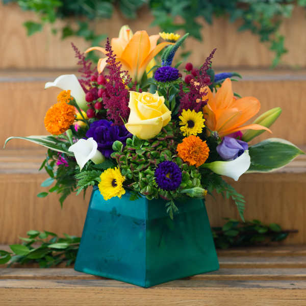 Colorful mixed flower arrangement in a teal vase