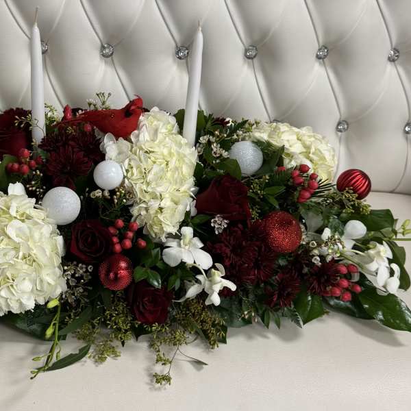 Low floral centerpiece with white hydrangeas, red roses, and candles