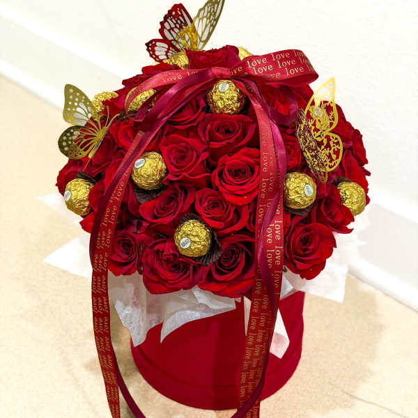 Red rose bouquet with gold chocolates and butterfly decorations in a red box