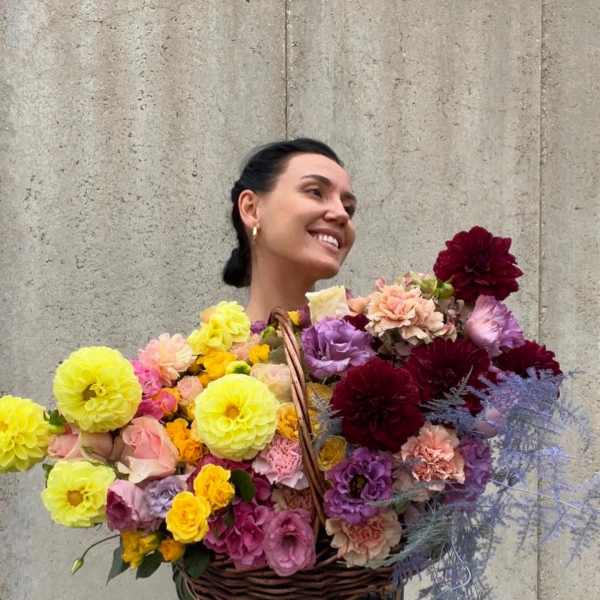 Woman holding a large basket of colorful flowers