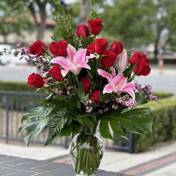 Red roses and pink lilies arranged in a clear glass vase
