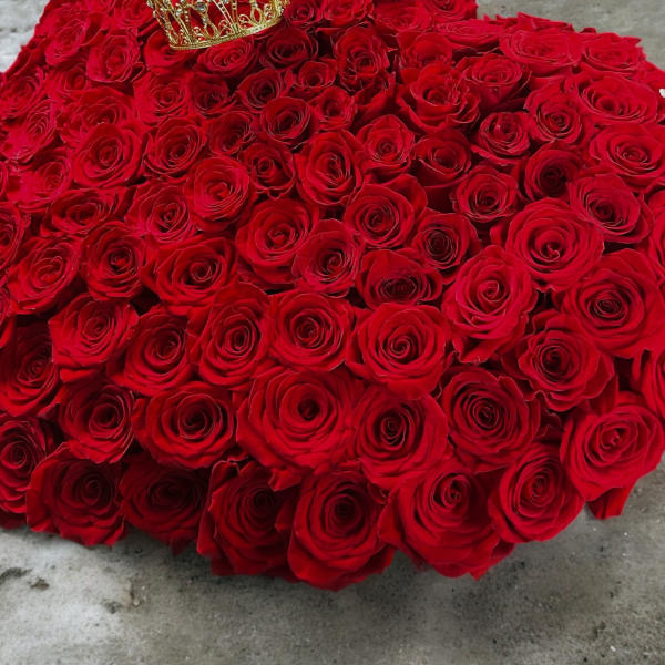 Heart-shaped arrangement of red roses with a gold crown on top