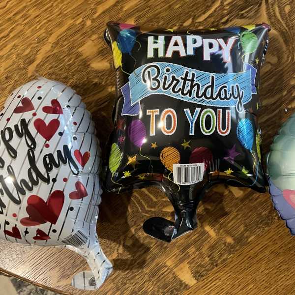 Three birthday foil balloons on a wooden table