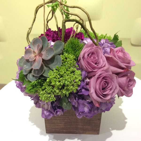 Purple roses and succulents in a wooden box with twig handles