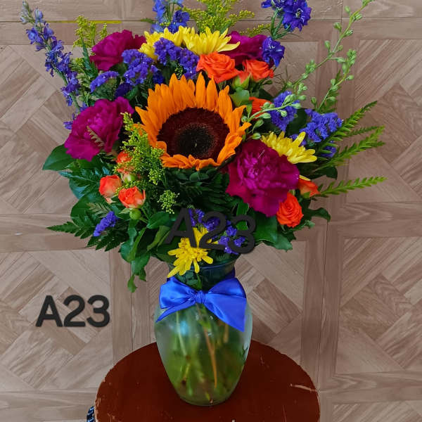 Colorful bouquet with a sunflower in a glass vase tied with a blue ribbon
