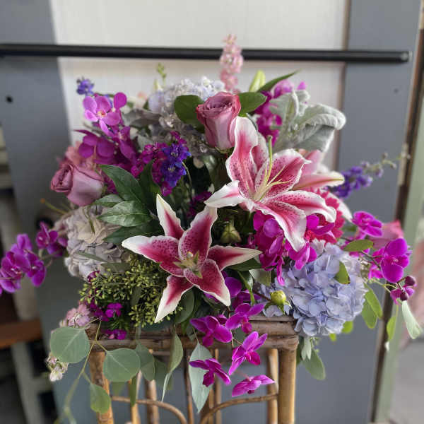 Mixed bouquet with pink lilies, roses, and purple orchids in a basket