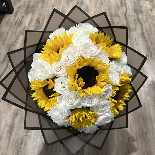 Bouquet of white roses and yellow sunflowers wrapped in black paper