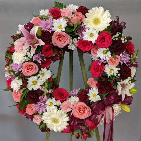 Heart-shaped floral wreath with pink, red, and white flowers on an easel