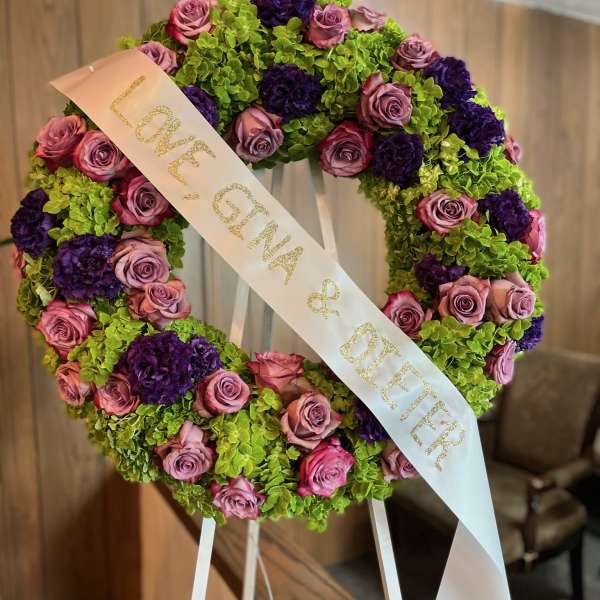 Heart-shaped floral wreath with pink roses, purple blooms, and a ribbon