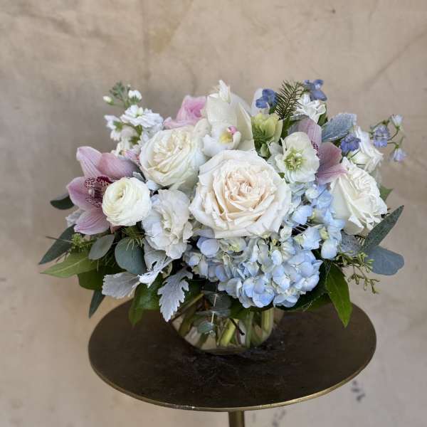Pastel bouquet of roses, hydrangeas, and orchids in a glass vase