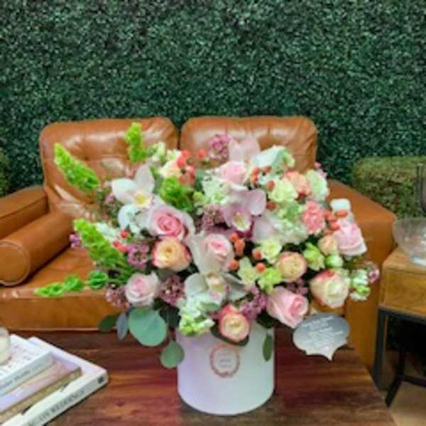 Large pastel bouquet in a white hatbox on a wooden table
