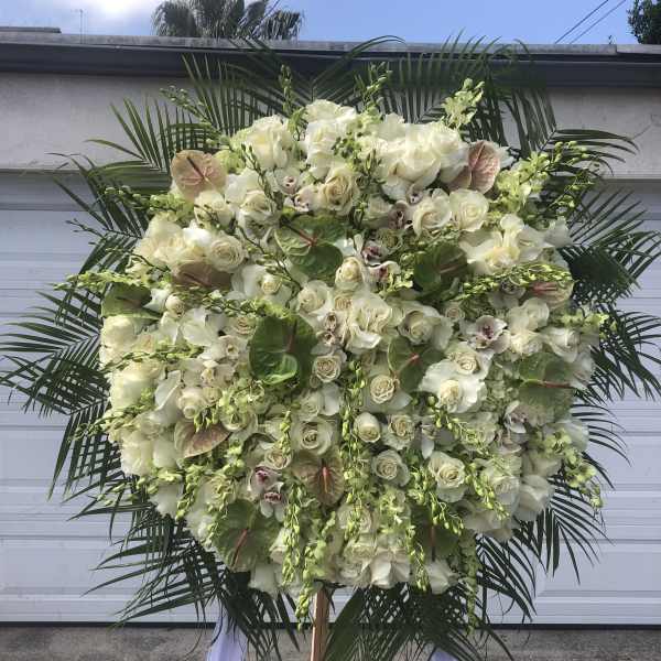 Large white floral standing spray with palm fronds and orchids