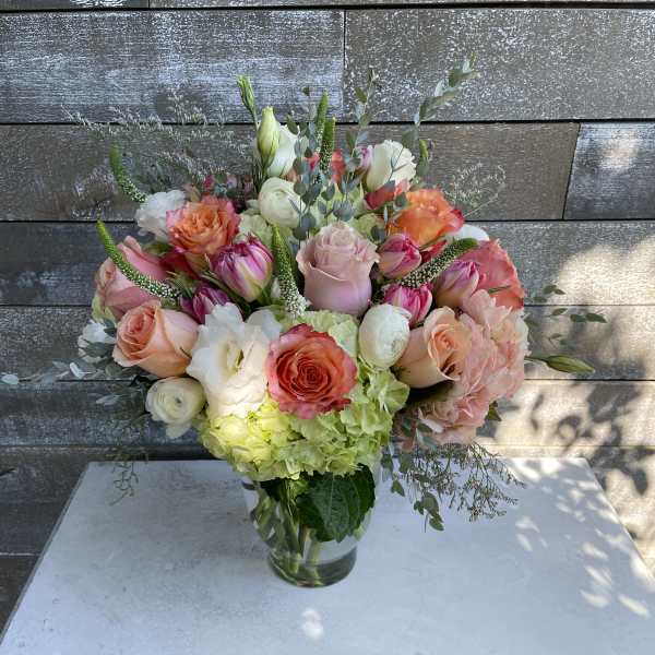 Mixed bouquet of roses, tulips, and hydrangeas in a glass vase