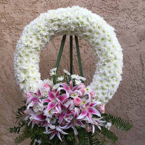 White floral funeral wreath with pink lilies and roses
