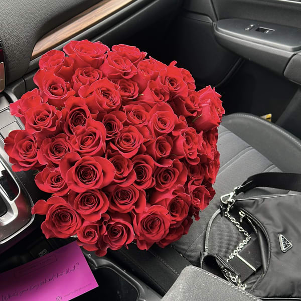 Large round bouquet of red roses resting on a car seat