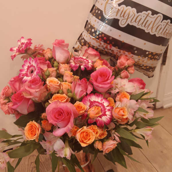 Pink and orange mixed bouquet in a vase with a congratulatory balloon