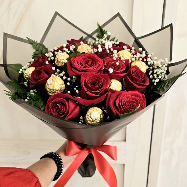 Bouquet of red roses with gold-wrapped chocolates and baby's breath
