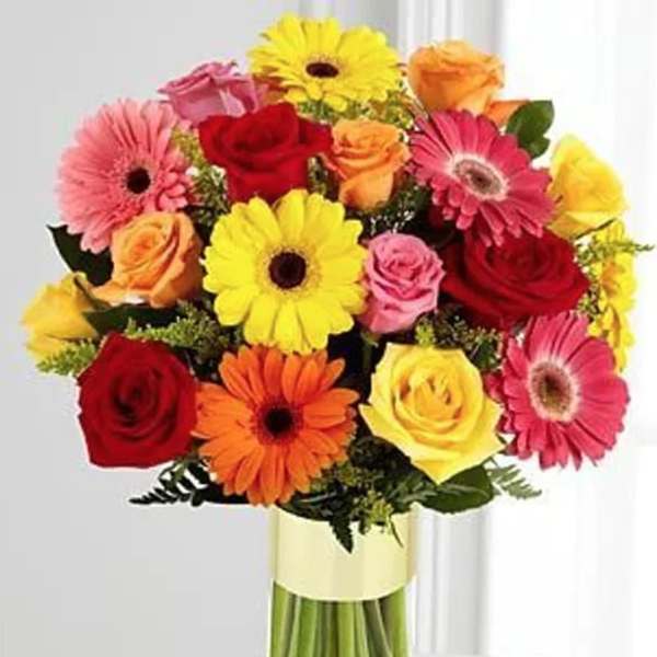 Colorful bouquet of gerbera daisies and roses in a glass vase