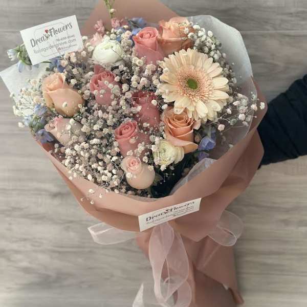 Bouquet of pink and peach roses with a pale gerbera daisy