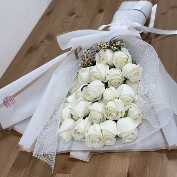 Bouquet of white roses wrapped in white mesh and paper