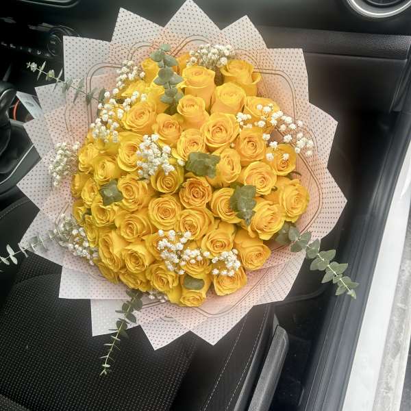 Bouquet of yellow roses with baby's breath and eucalyptus in pink wrap